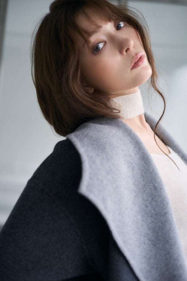 グレイ色のリバーロングコートと中に後ろ開きモヘアニット着てるモデルの横の姿