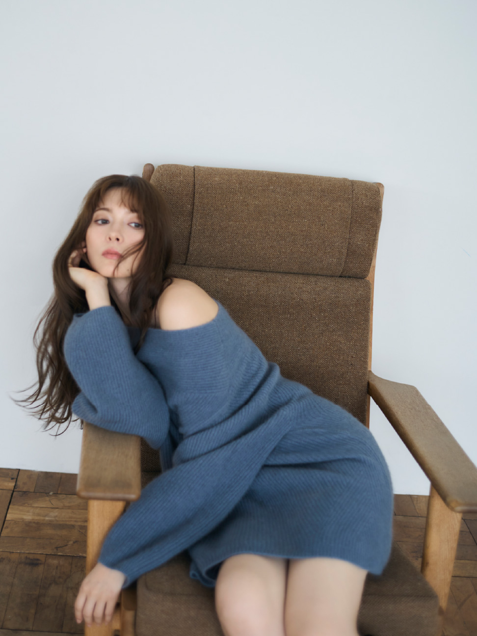 ラクーンニットミニドレスを着用して茶色の椅子に座ってる女性