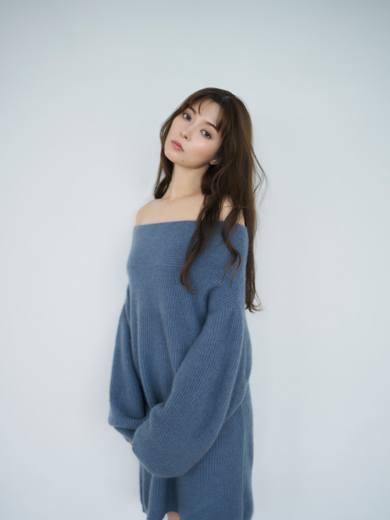 青色のラクーンニットミニドレスを着てる女性の横の姿