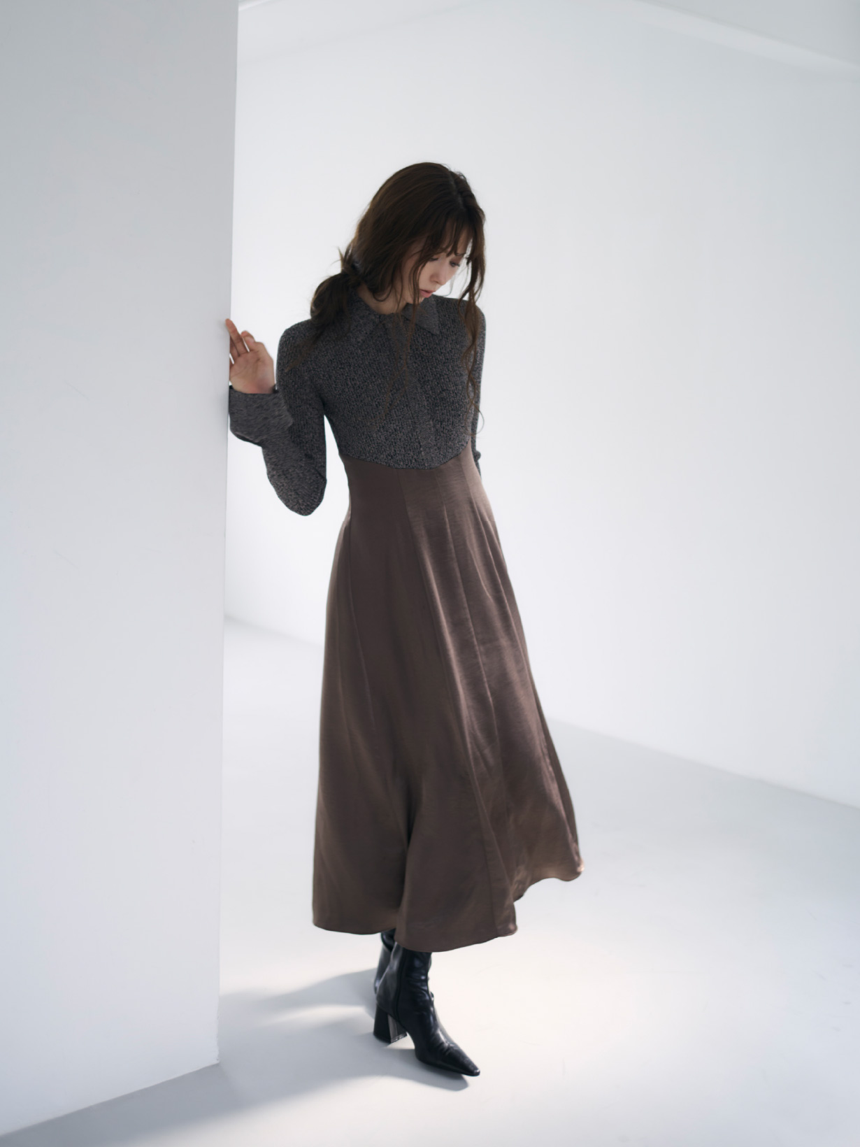 茶色のポロカラーニットワンピースと黒色のセミスクエアトゥストレッチブーツを着用してる女性