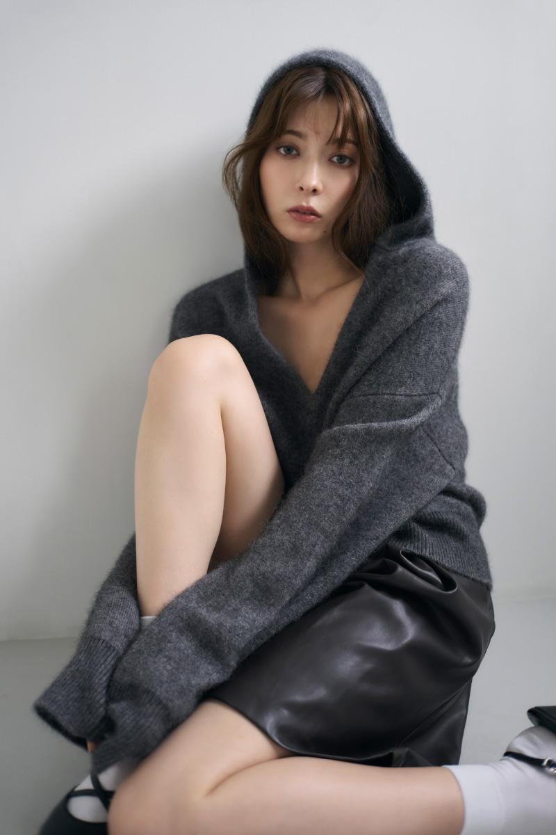 グレイ色のショートニットフーディーや黒色のタックハーフパンツ、パールリングフープピアスを着用してる女性