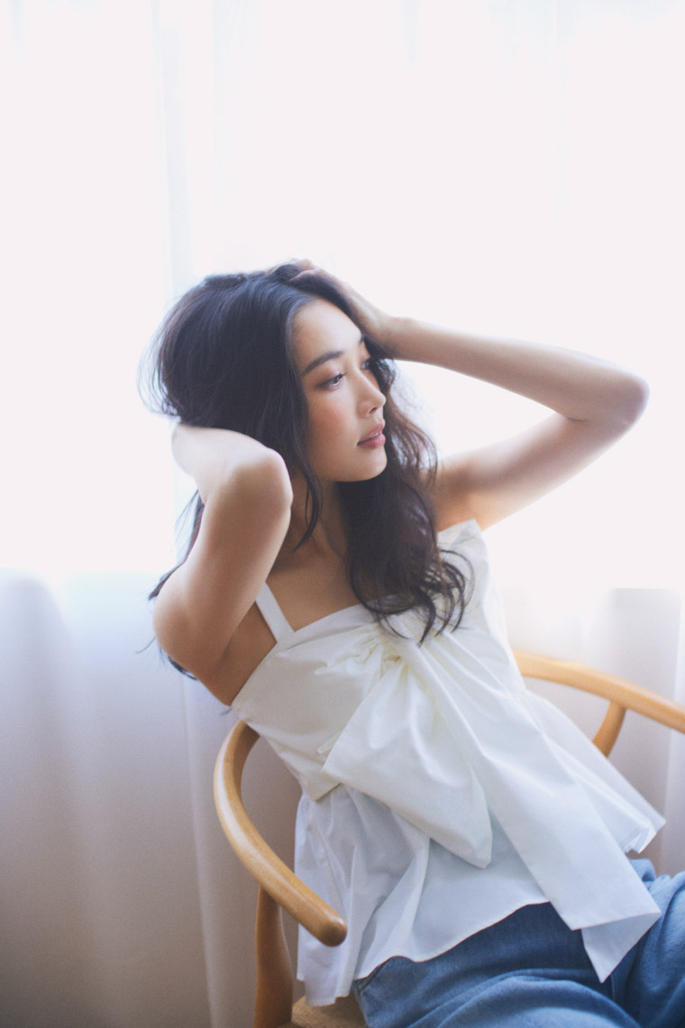 ライトグレーのジャケット・ホワイトのトップス・ブルーのデニムパンツを履いた女性