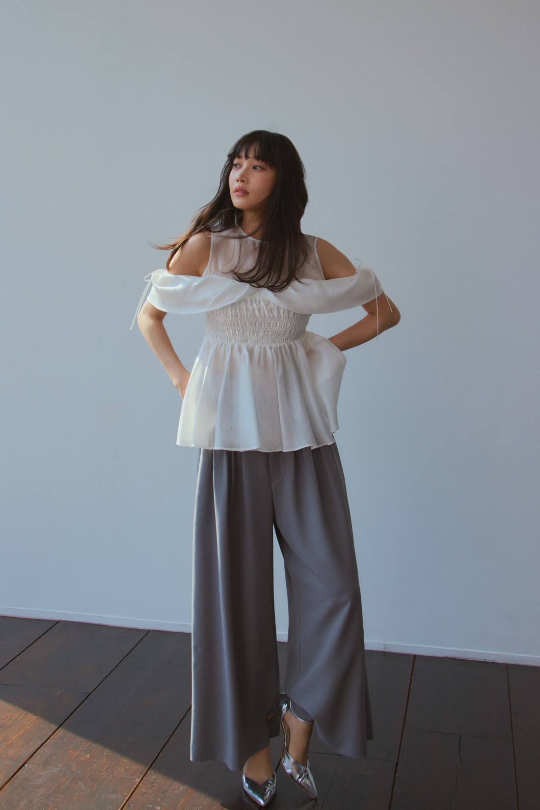 オフショルペプラムブラウス・ハイウエストワイドレッグパンツ・２ｗａｙパールフープピアス・アンクルストラップパンプスを着用した女性