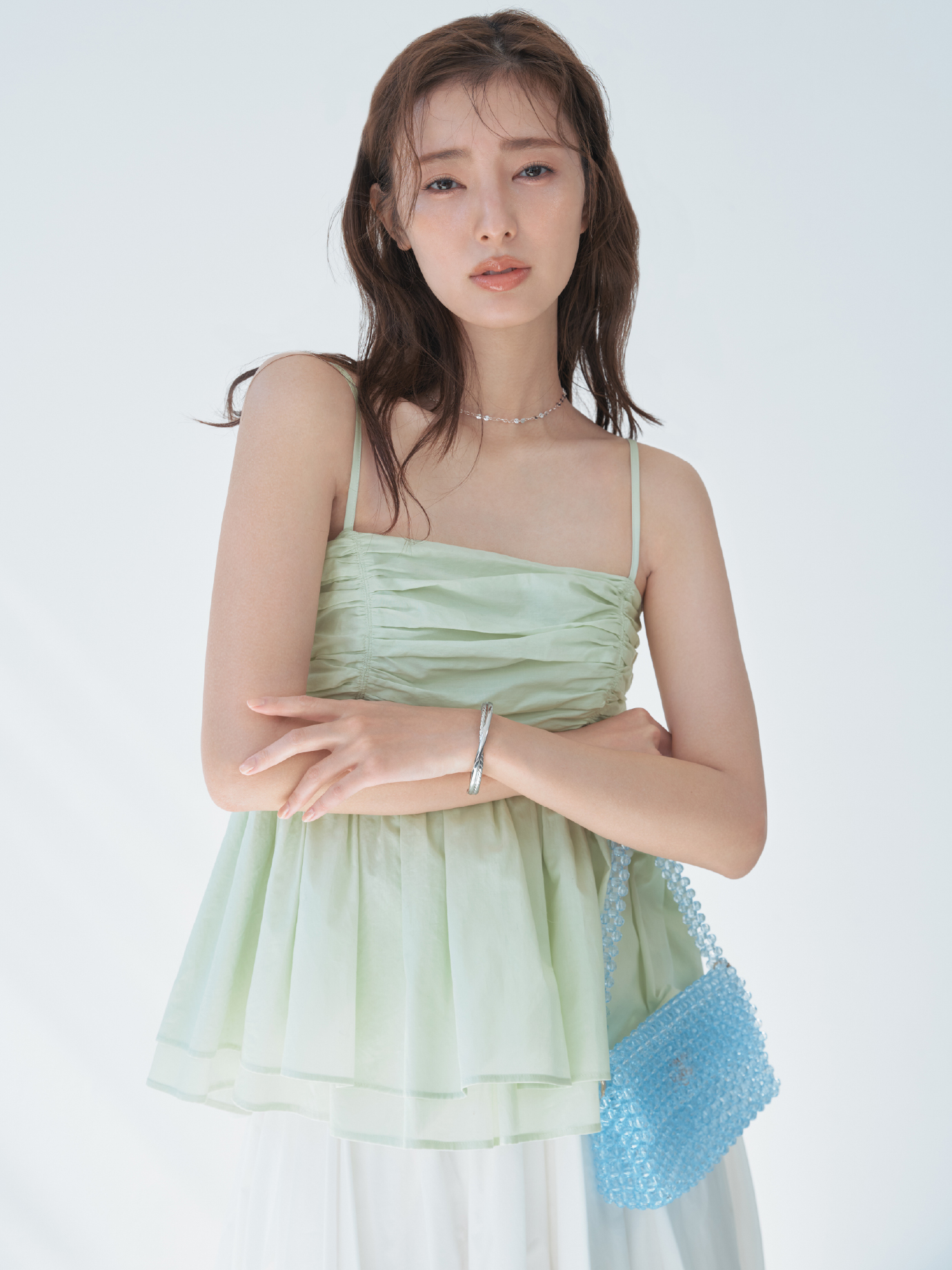 バックシャンペプラムギャザーキャミソールライトタフタリボンスカート・MIXパーツネックレス・クロスラインバングル・フルーツモチーフビーズバッグを着用した女性