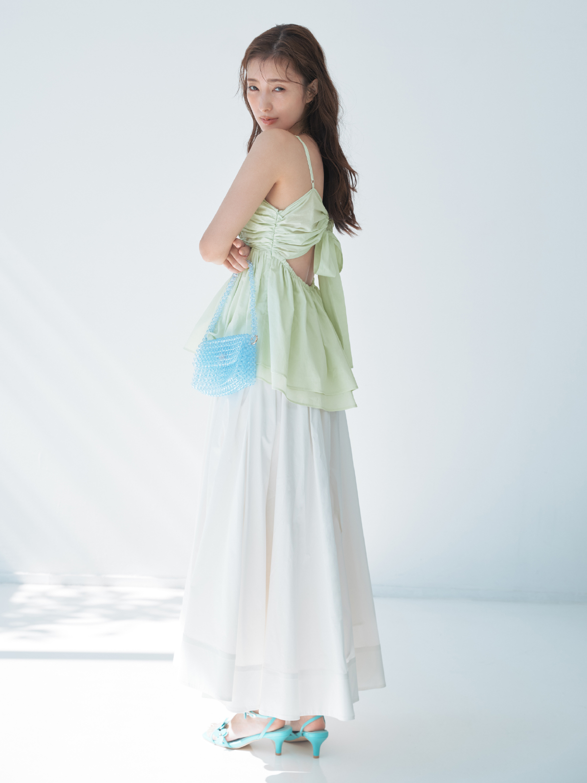 バックシャンペプラムギャザーキャミソールライトタフタリボンスカート・MIXパーツネックレス・クロスラインバングル・フルーツモチーフビーズバッグ・フラワーモチーフストラップサンダルを着用した女性