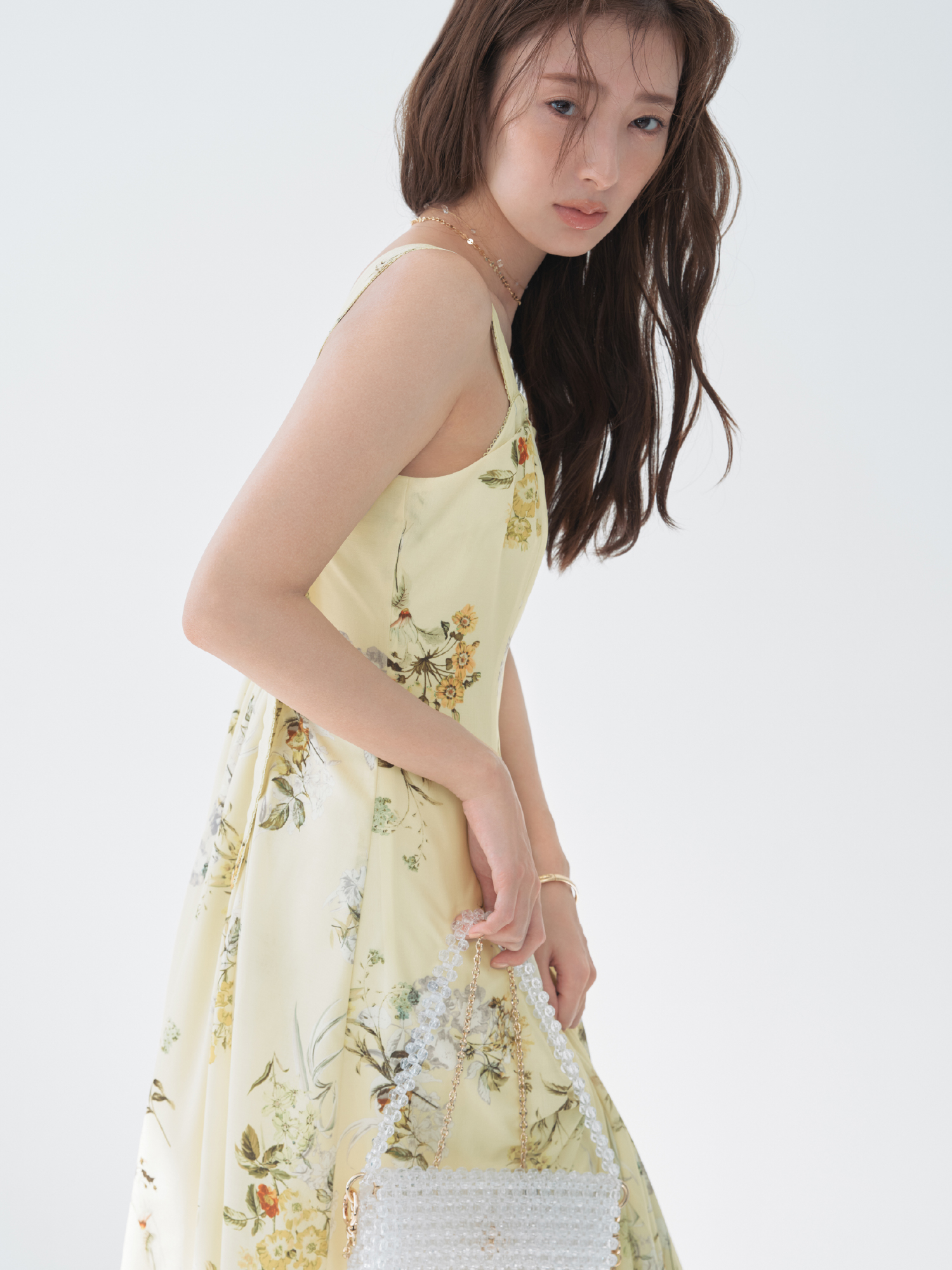 レイヤードライクフラワーワンピース・MIXパーツネックレス・クロスラインバングルを着用した女性