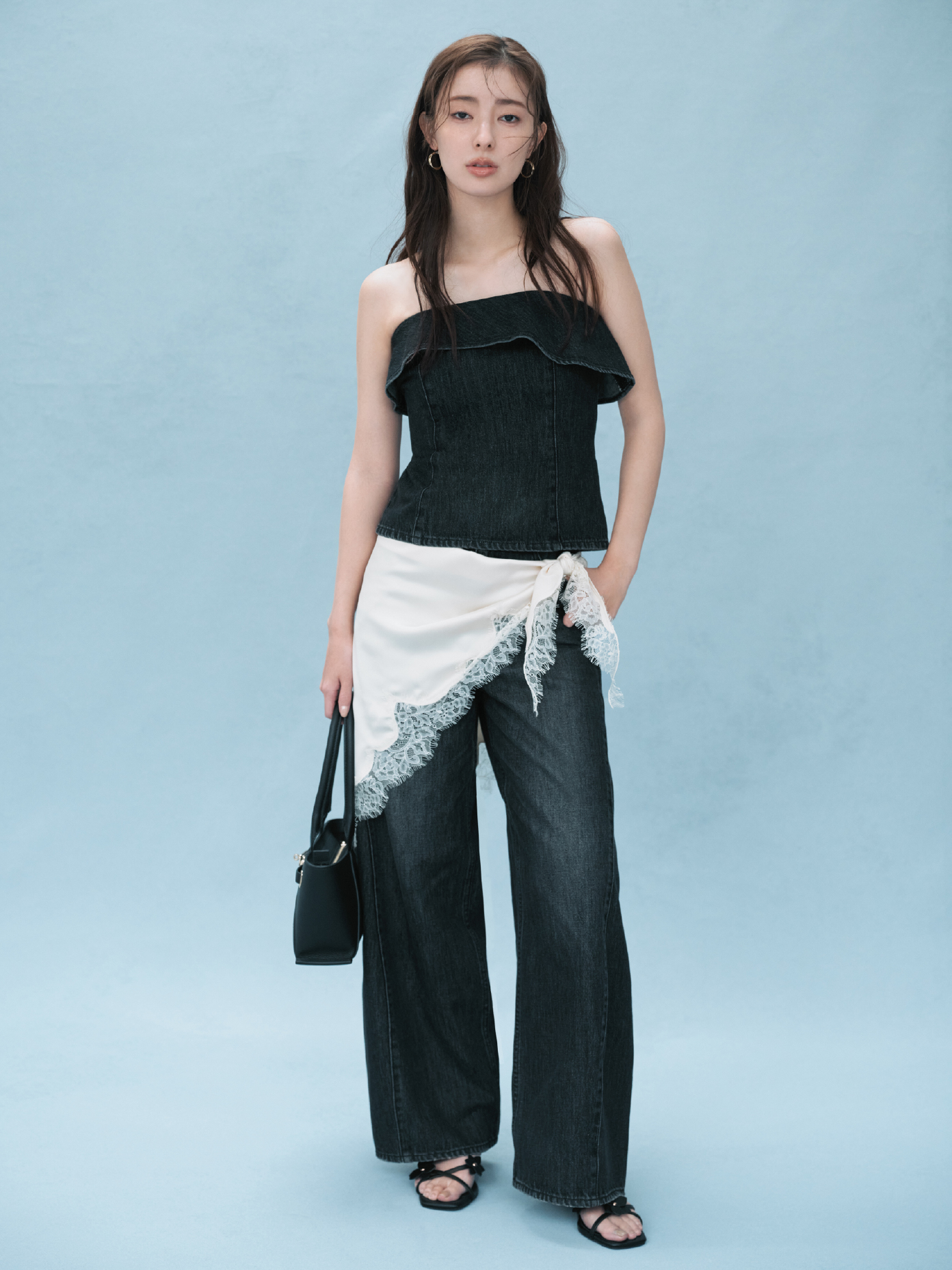 2wayデニムビスチェ・バレルフォルムデニムパンツ・クロスラインフープピアス・レーストリムスカーフ・ベルトデザインレザートートバッグ・フラワーモチーフストラップサンダルを着用した女性