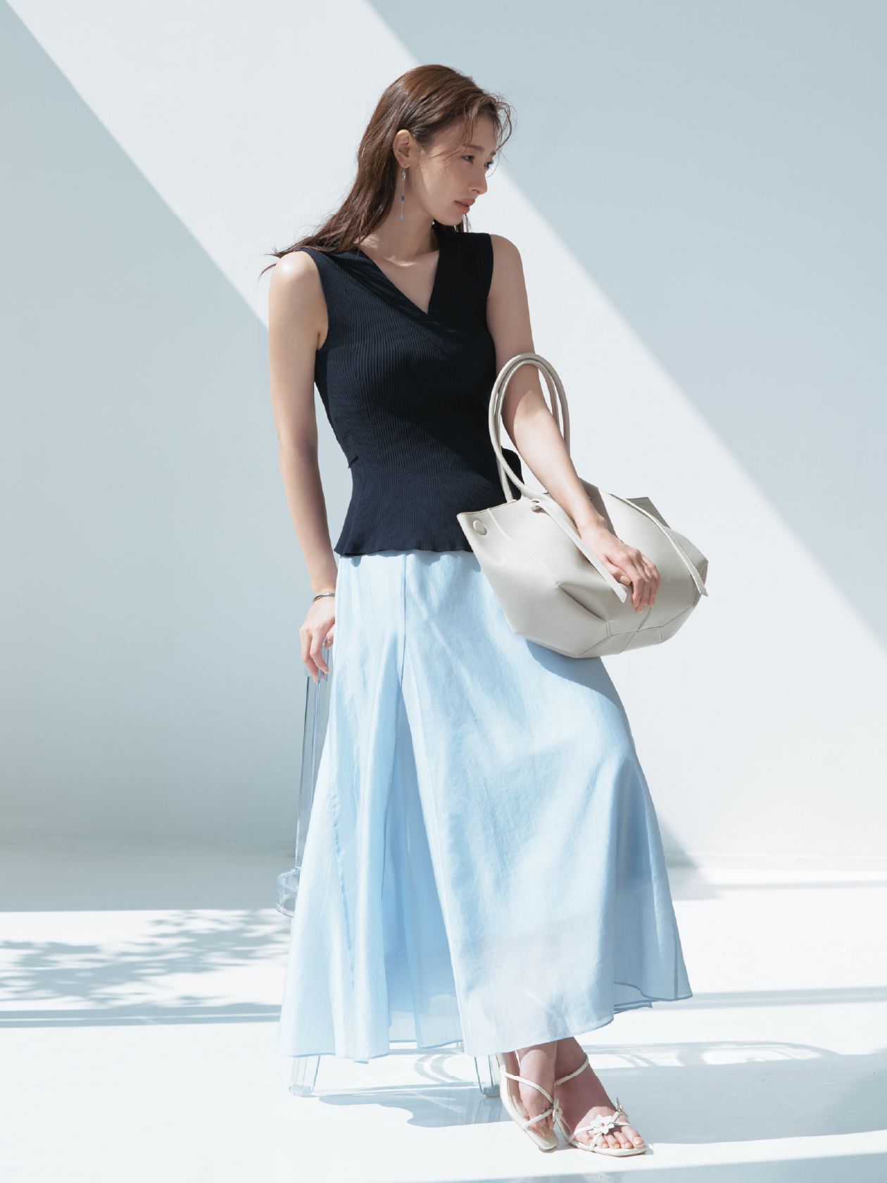 2wayニットセットアップワンピース・MIXパーツピアス・クロスラインバングル・ベルトデザイントートバッグ・フラワーモチーフストラップサンダルを着用した女性