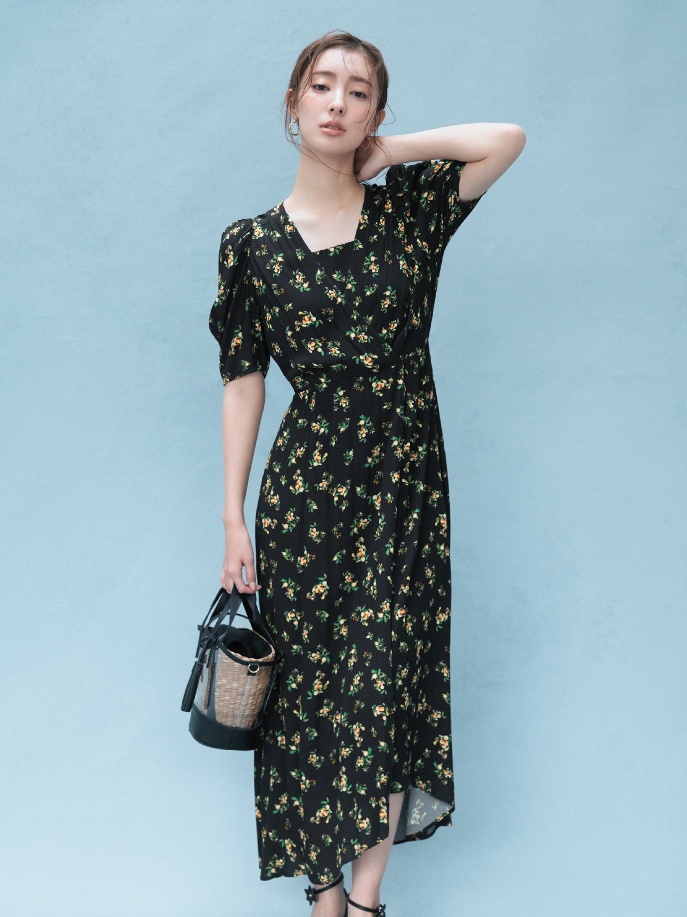 フルーツプリントレーヨンワンピース・クロスラインフープピアス・【BAGMATI】ビニールカゴバッグ(別注カラー)・フラワーモチーフストラップサンダルを着用した女性