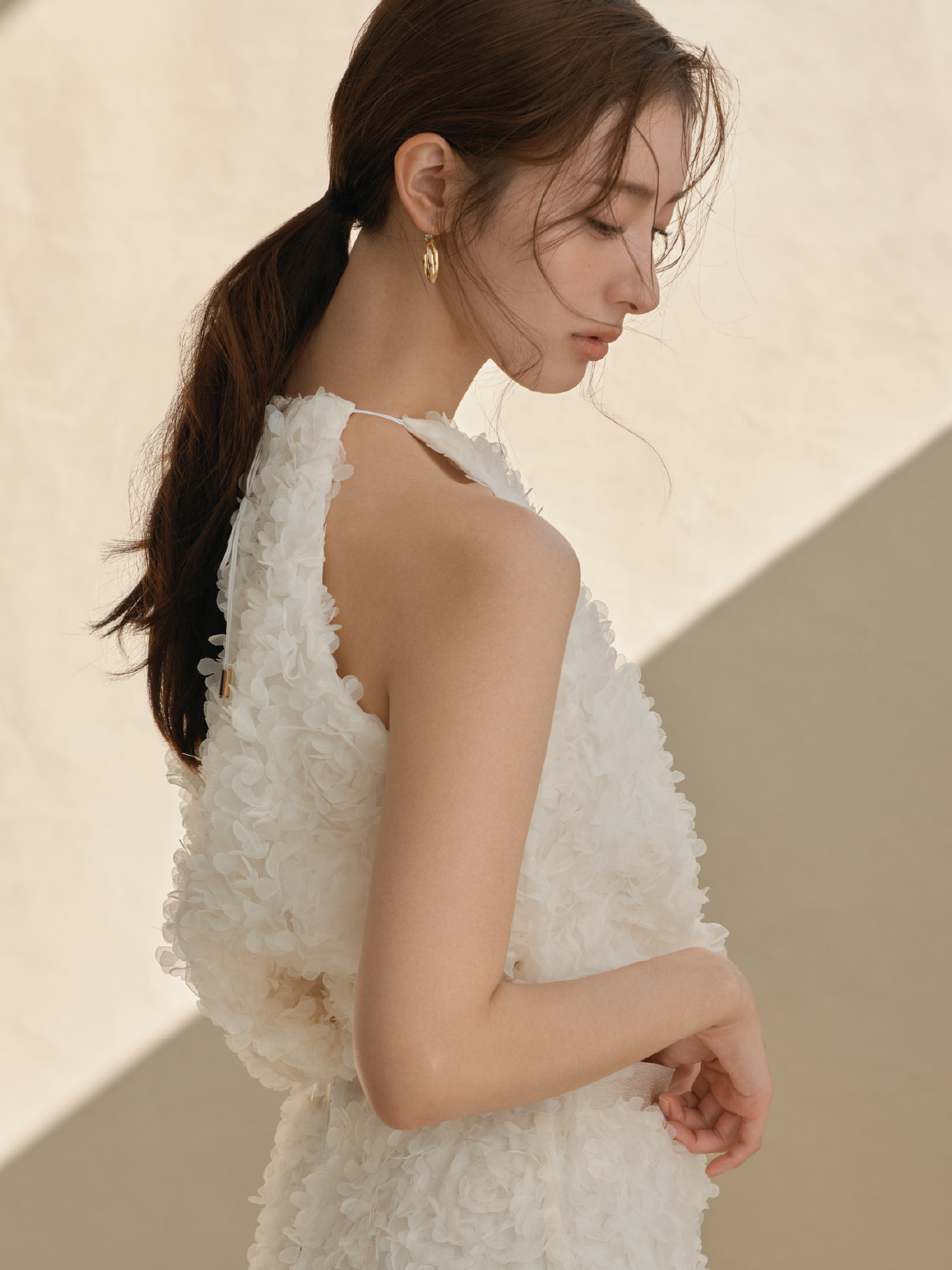 3Dフラワーホルターネックブラウス・3Dフラワーストレートスカート・クロスラインフープピアス・クロスラインバングルを着用した女性