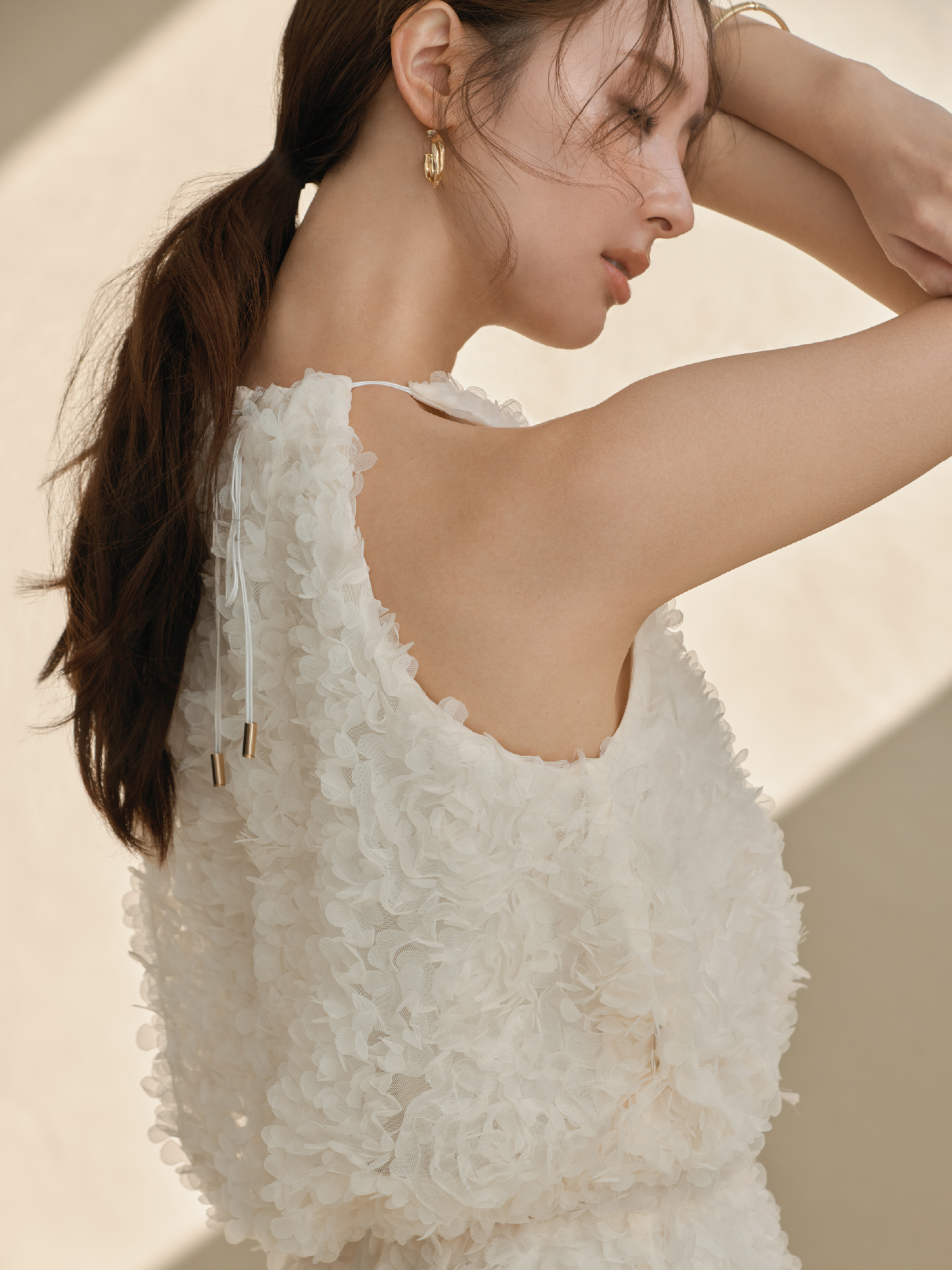 3Dフラワーホルターネックブラウス・3Dフラワーストレートスカート・クロスラインフープピアス・クロスラインバングルを着用した女性