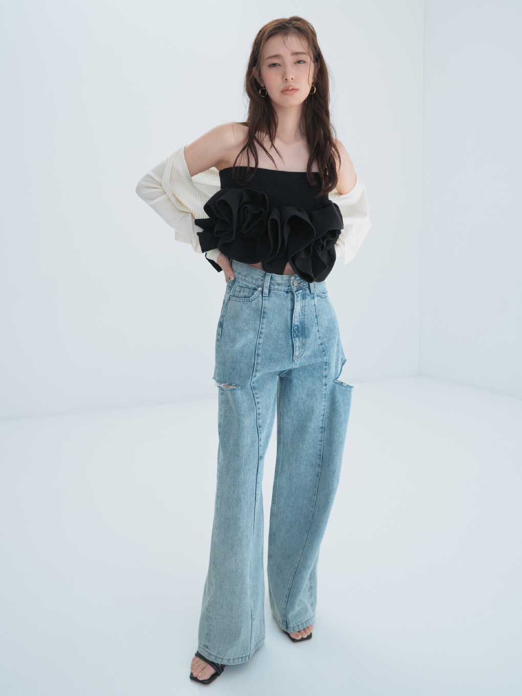 セミシアークロップドリブカーディガン・【00サイズあり】カットアウトバレルデニムパンツ・フラワーペプラムニットベアトップス・クロスラインフープピアス・クリアヒールサンダルを着用した女性