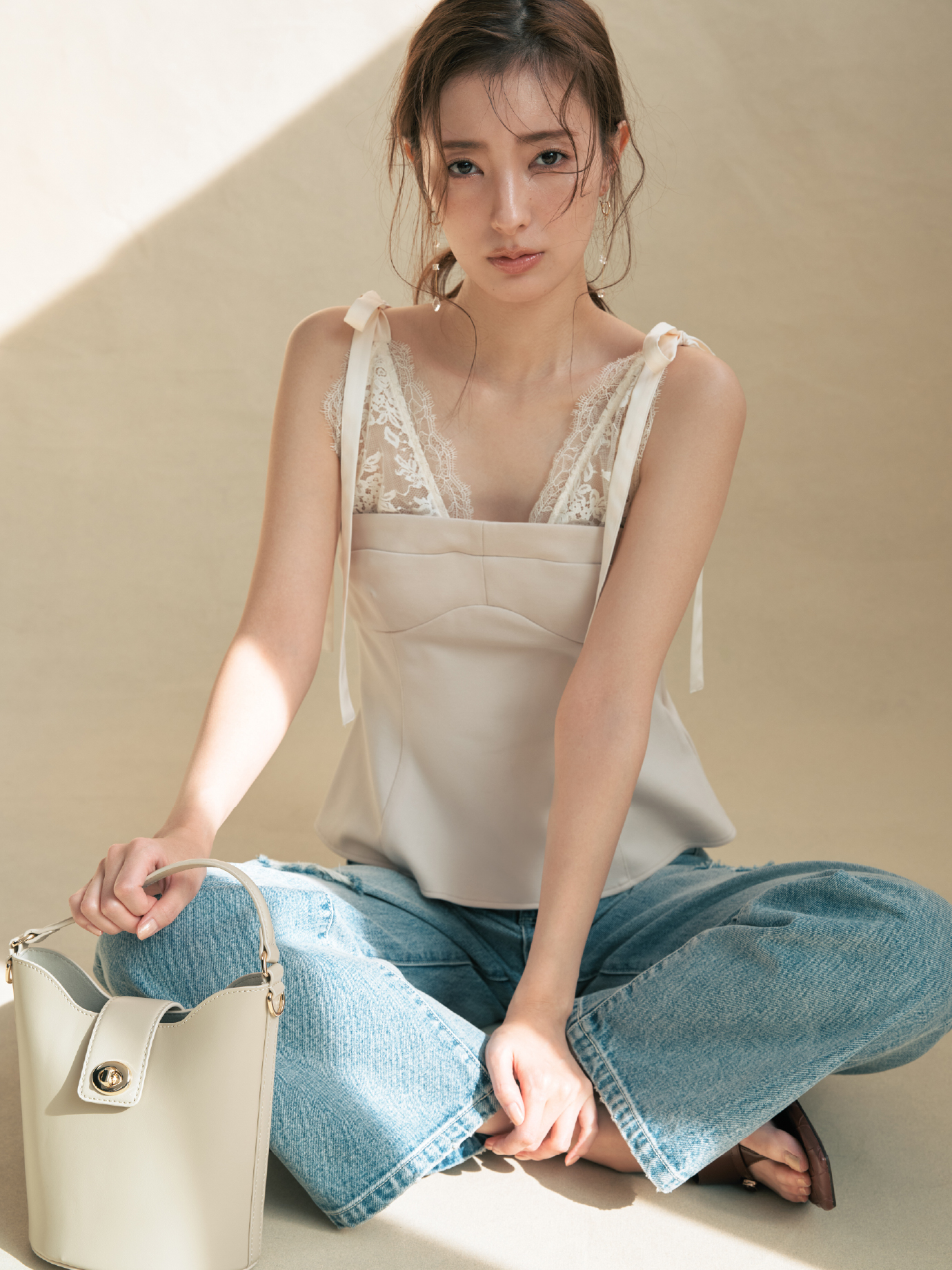 レースレイヤードビスチェ・ハイライズダメージデニムパンツ・MIXパーツピアス・レザーバスケットバッグ・トングウェッジサンダルを着用した女性