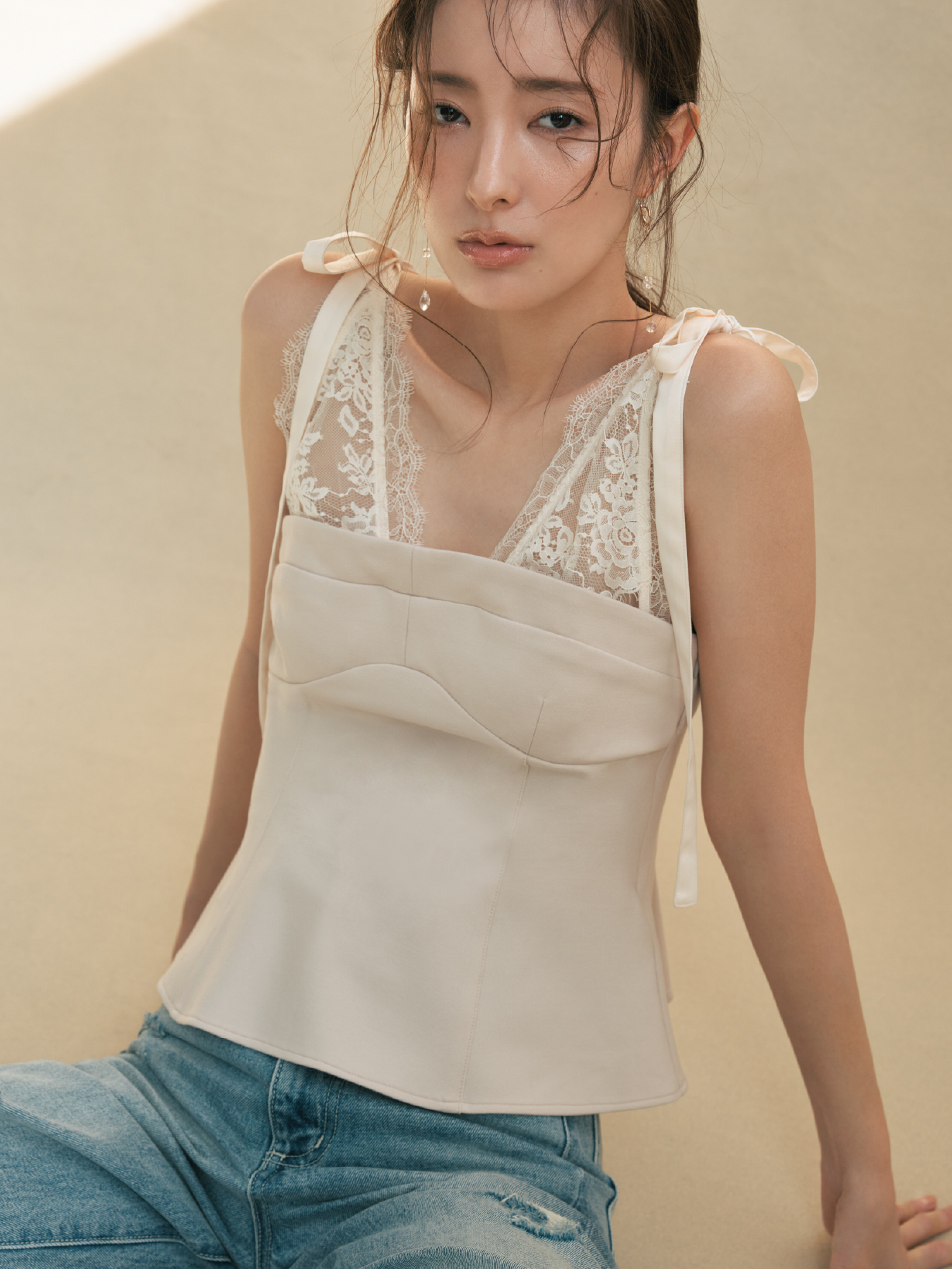 レースレイヤードビスチェ・ハイライズダメージデニムパンツ・MIXパーツピアスを着用した女性