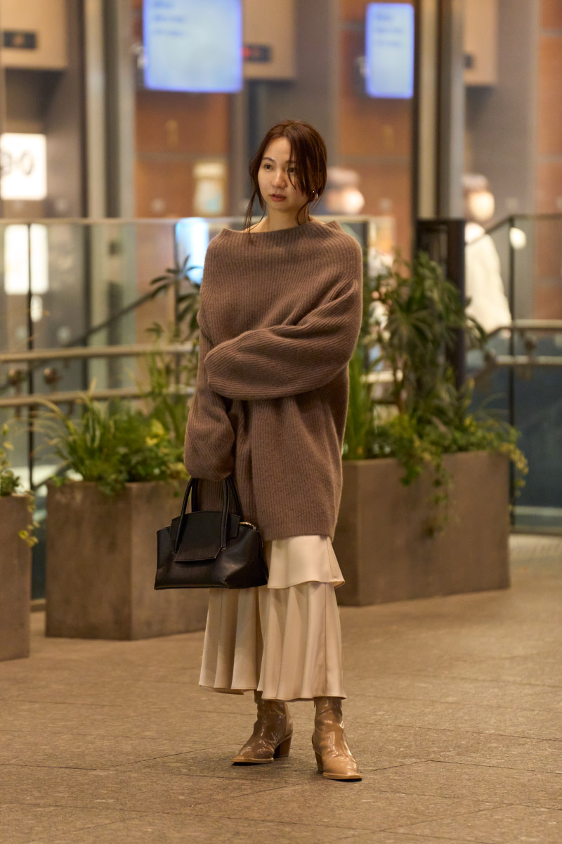 ブラウンのトップス・アイボリー色のスカートを履いた女性