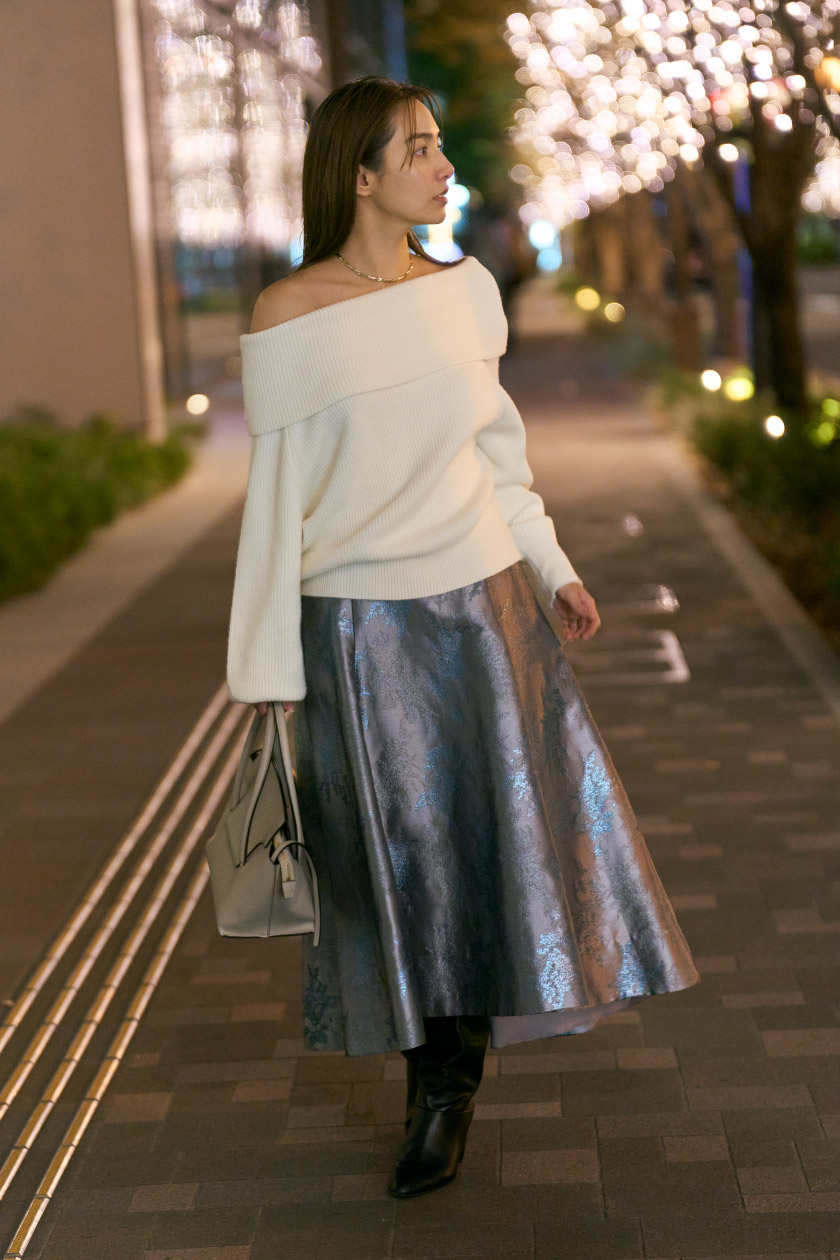 オフホワイトのトップス・グレーのスカートを履いた女性