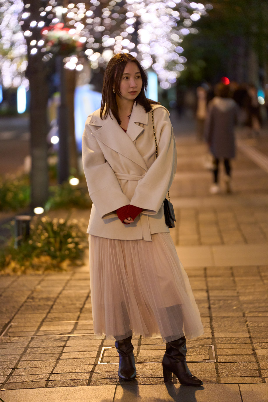 アイボリーのコート・赤のニットドレス・黒のロングブーツを履いた女性