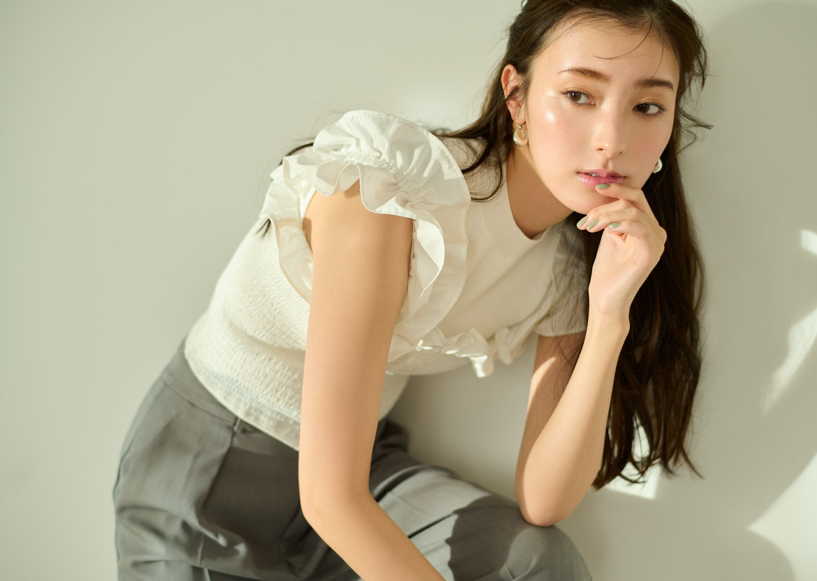 シャーリングブラウスセットニット・ツイルタックストレートパンツ・ワンタッチミニフープピアス・ラフィアミニショルダー・バックルフラットパンプスを着用した女性