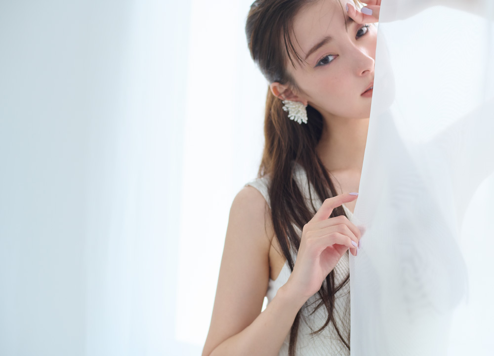 カシュクールニットコンビＯＰ・シャワーパールイヤリング・クリアストラップサンダルを着用した女性