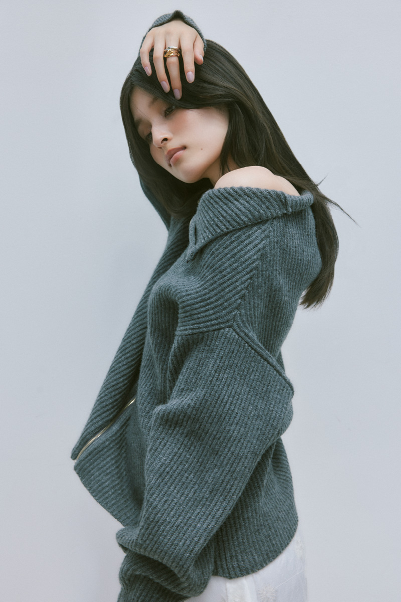 グレー色の2wayオフショルスキッパージップニットを着用した女性の横の姿