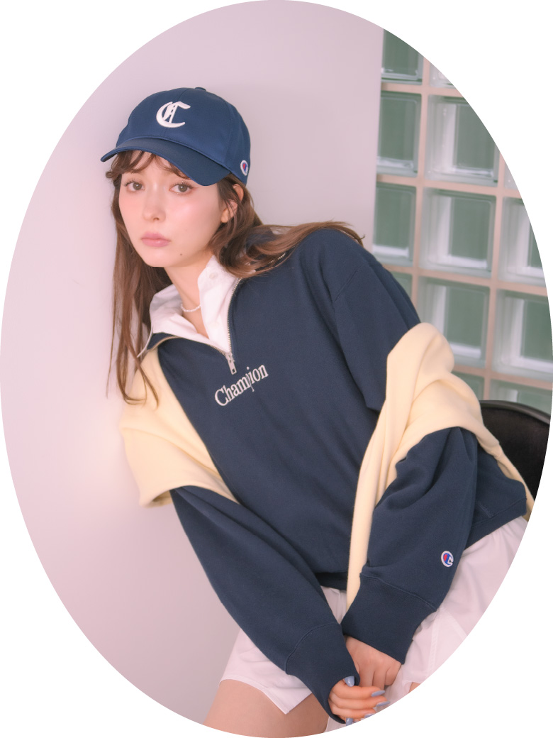 ネービー色の【Champion】リバースウィーブハーフジッププルオーバーと【Champion】オリジナルロゴキャップ、白いボーイフレンドシャツミニワンピースを着用したモデル画像