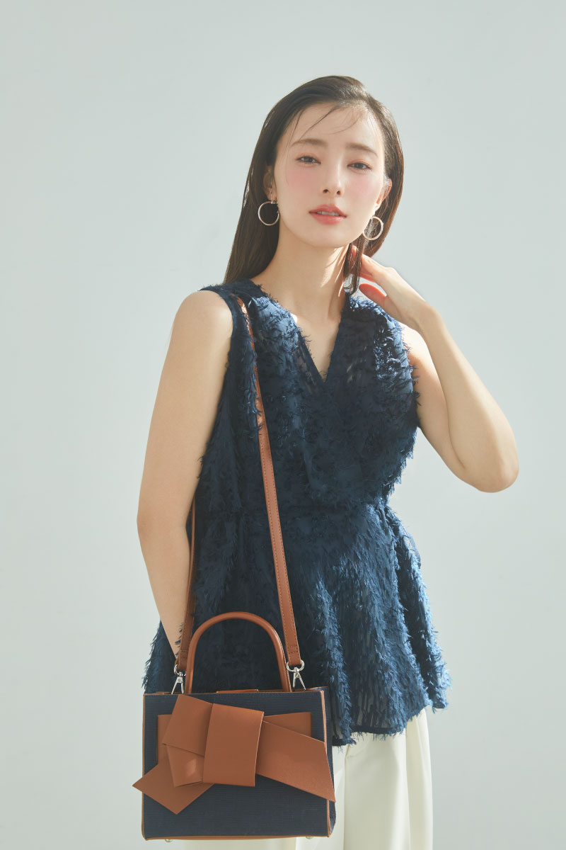 ネービー色のフリンジブラウスと【LIMITED】【ルエル】デニム風リボンミドルバッグ、アイボリー色のスリータックハイウエストツイルワイドパンツ、Silver２ｗａｙフープピアスを着用した女性