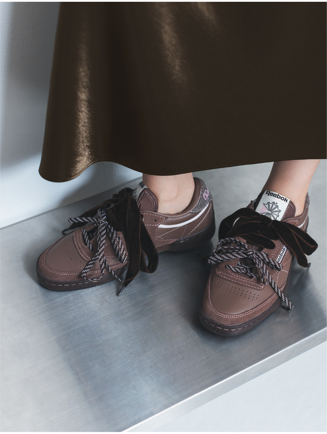 ハイウエストサテンナロースカート・【Reebok】スニーカーを着用した女性