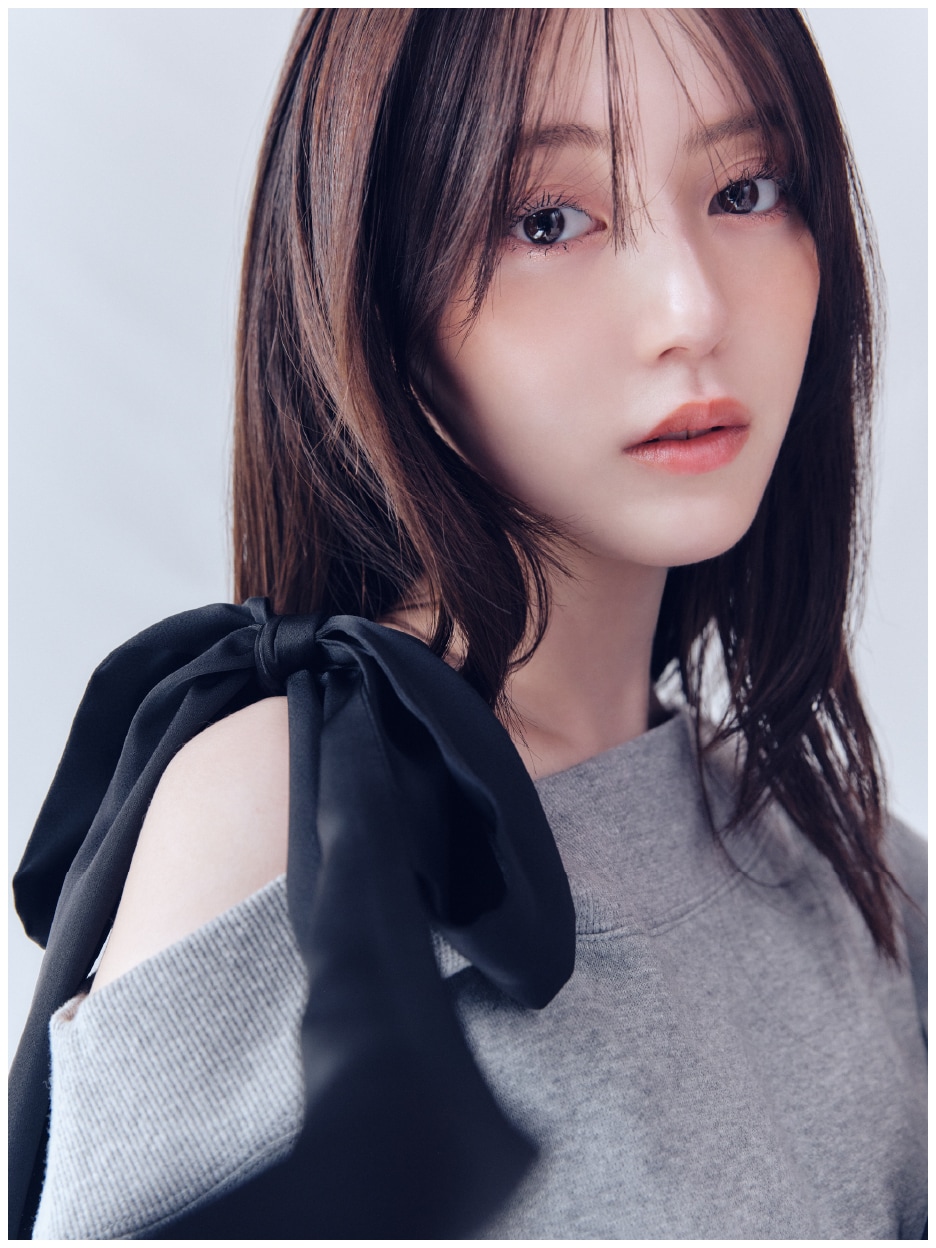 グレーのビッグリボンワンショルカットソーと白地にドット柄のハイウエストサテンナロースカート、黒のノットドローストリングバックとラウンドトゥロングブーツの着用例