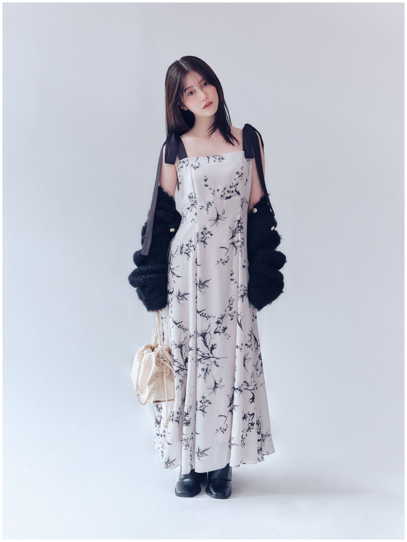 黒のモヘアシャギーニットカーディガン、リボンディテールフローラルワンピ、ノットドローストリングバックと黒のゲートルロングブーツの着用例