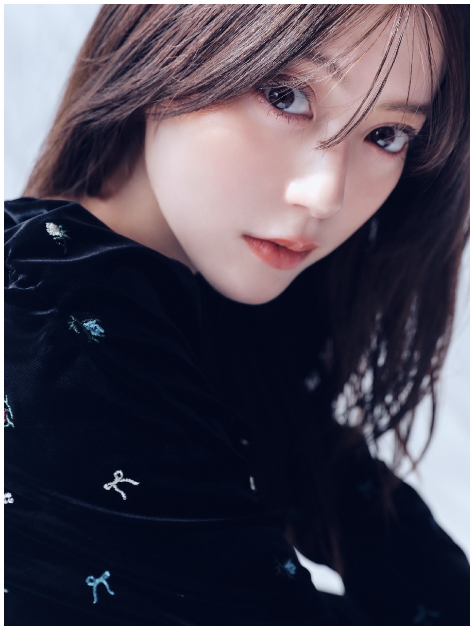 黒地にリボンモチーフを散らしたベロアナローワンピースを着た女性のアップ写真