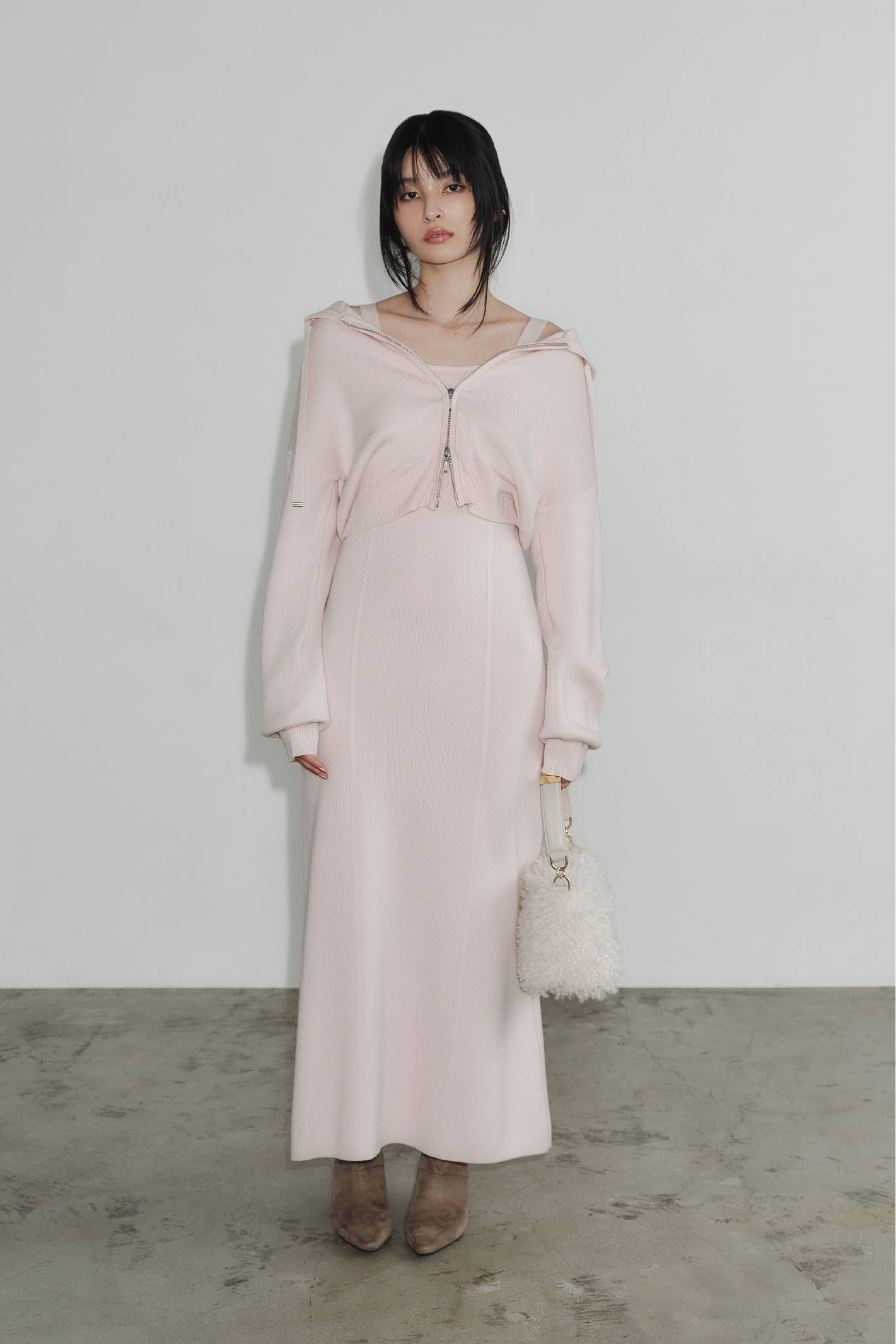 ジップパーカ&キャミワンピースセット・メタルモチーフワンハンドルファーバッグ・キトゥンヒールロングブーツを着用した女性の画像