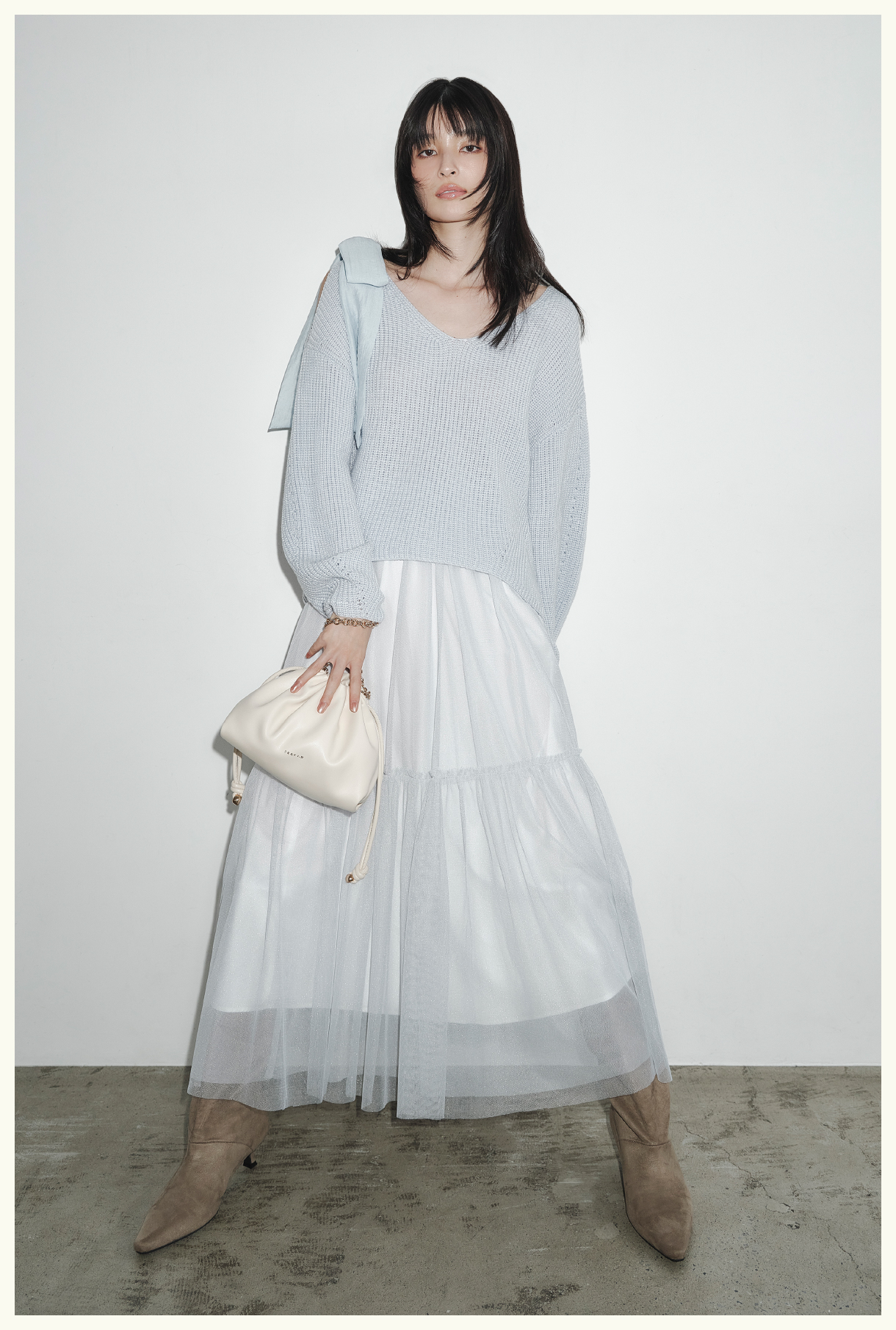 リボンニットプル＆チュールスカートセット・ノットドローストリングバック・キトゥンヒールロングブーツを着用した女性の画像