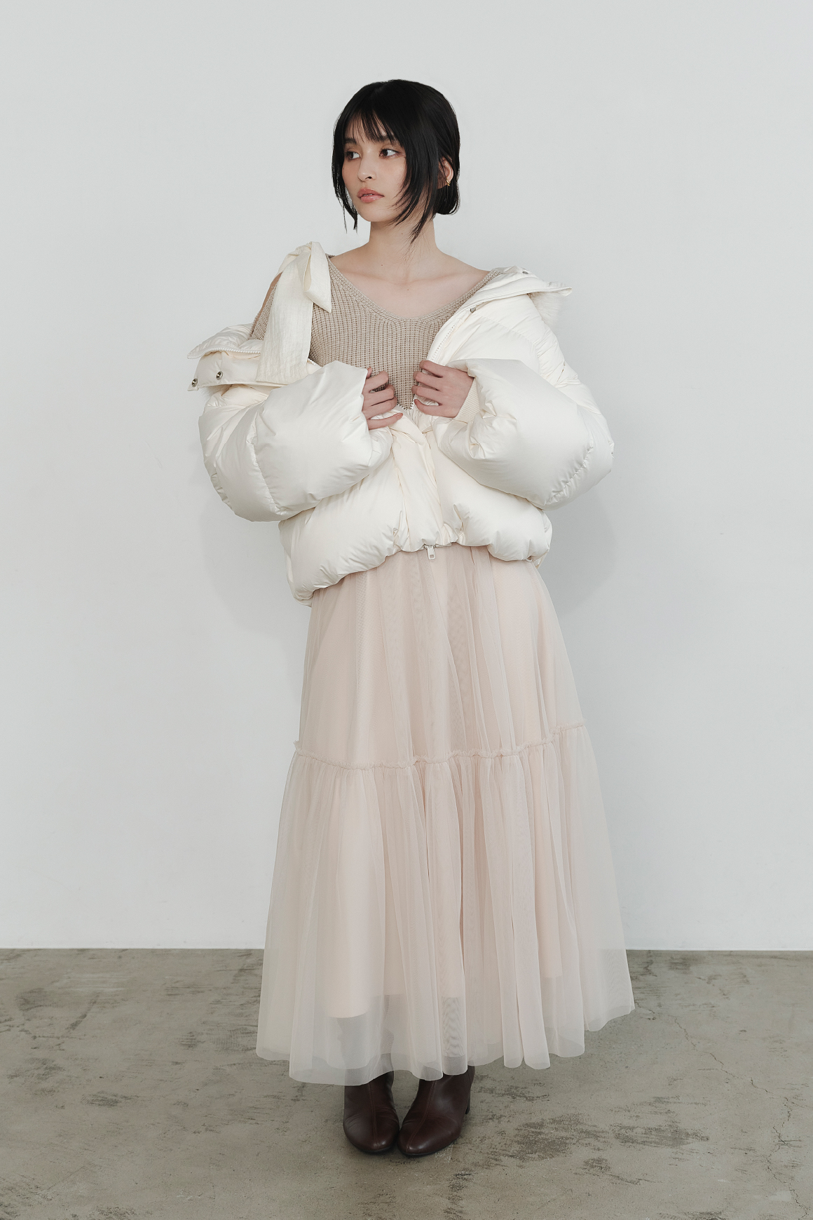 フードファーショートダウンコート・リボンニットプル＆チュールスカートセット・ラウンドトゥロングブーツを着用した女性の画像