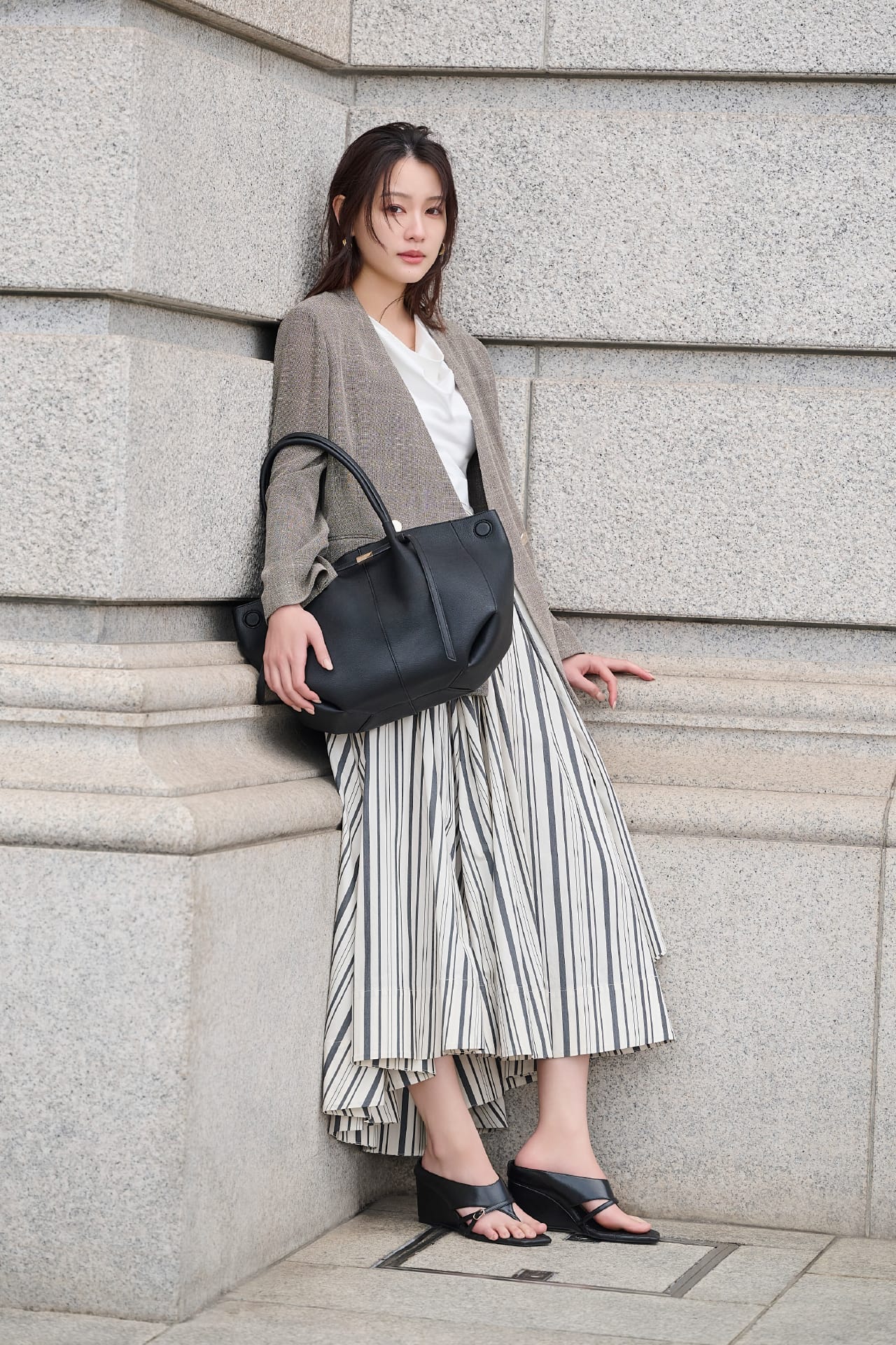 ベージュのジャケット・ストライプのスカートを着用した女性