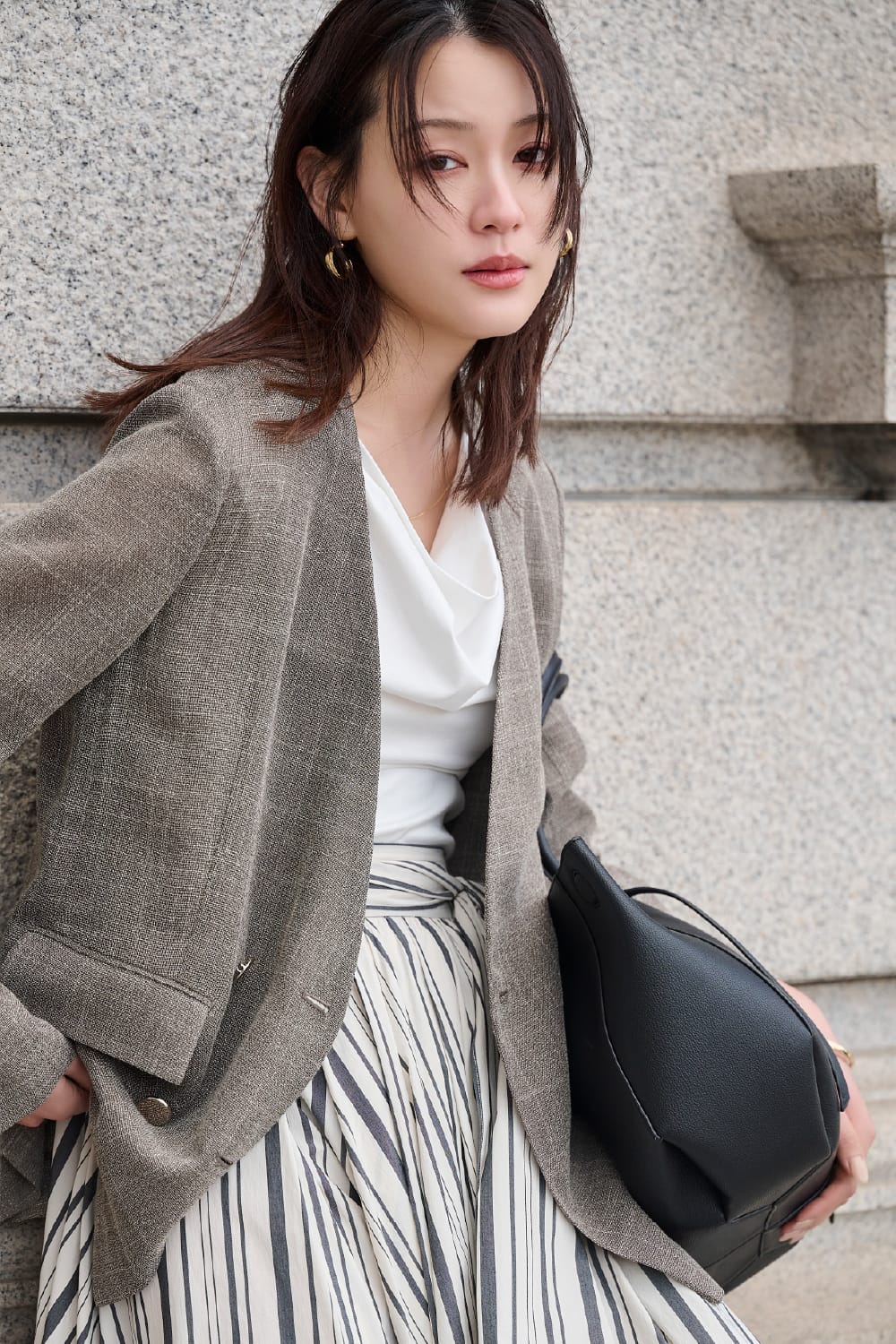 ベージュのジャケット・ストライプのスカートを着用した女性