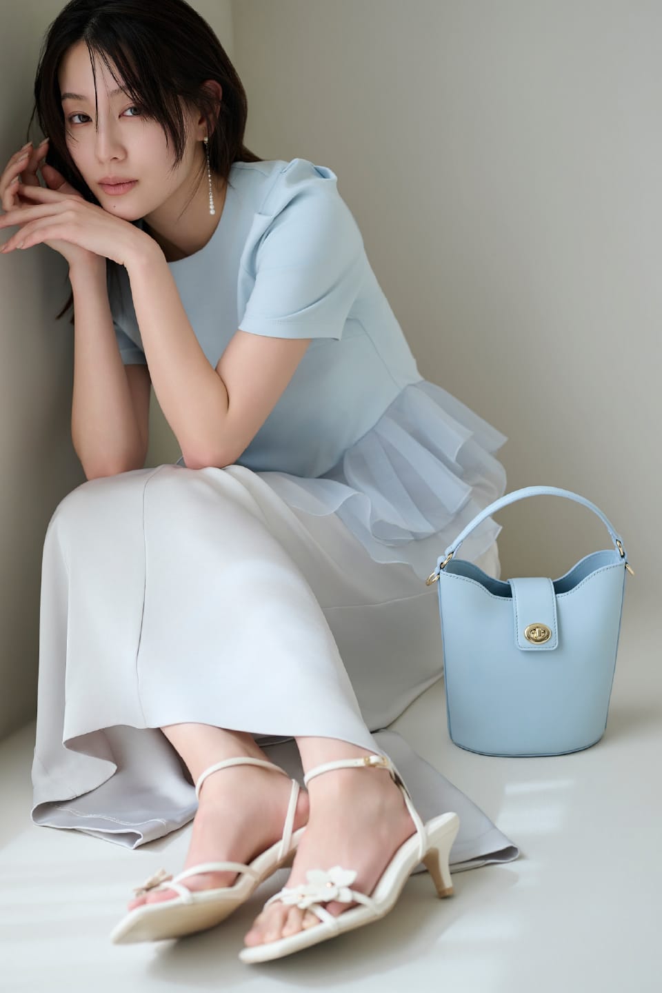 水色のトップスに白のスカートを着用している女性