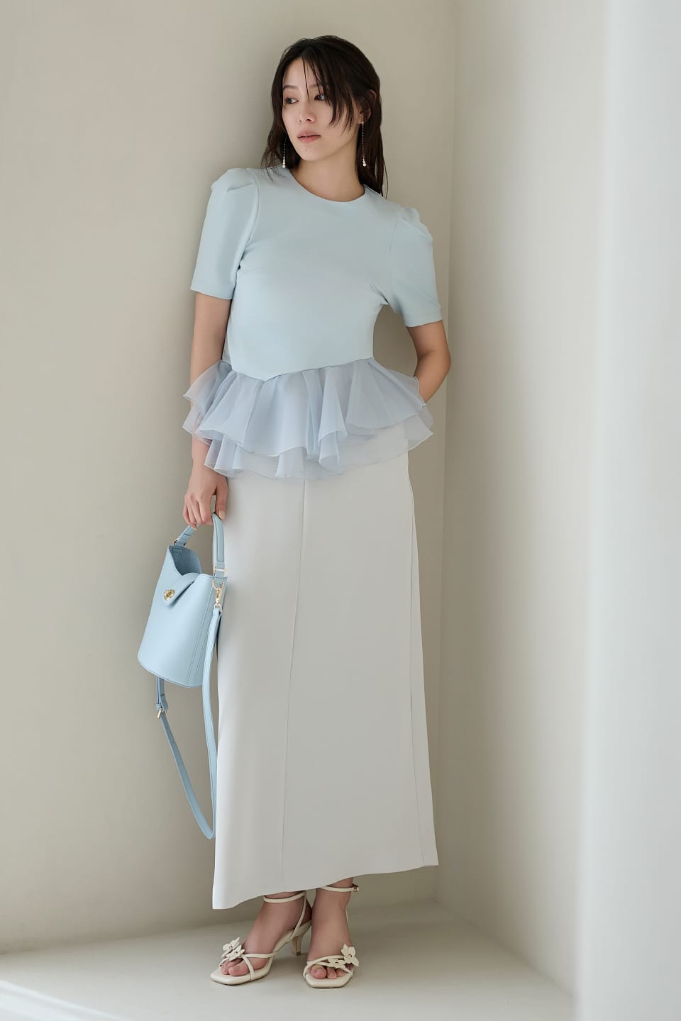 水色のトップスに白のスカートを着用している女性
