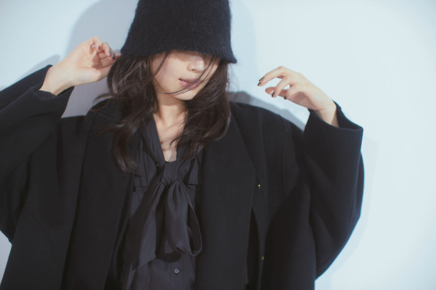 黒コート・黒ブラウス・黒パンツを履いた女性