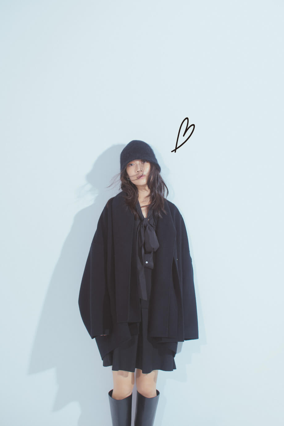黒コート・黒ブラウス・黒パンツを履いた女性