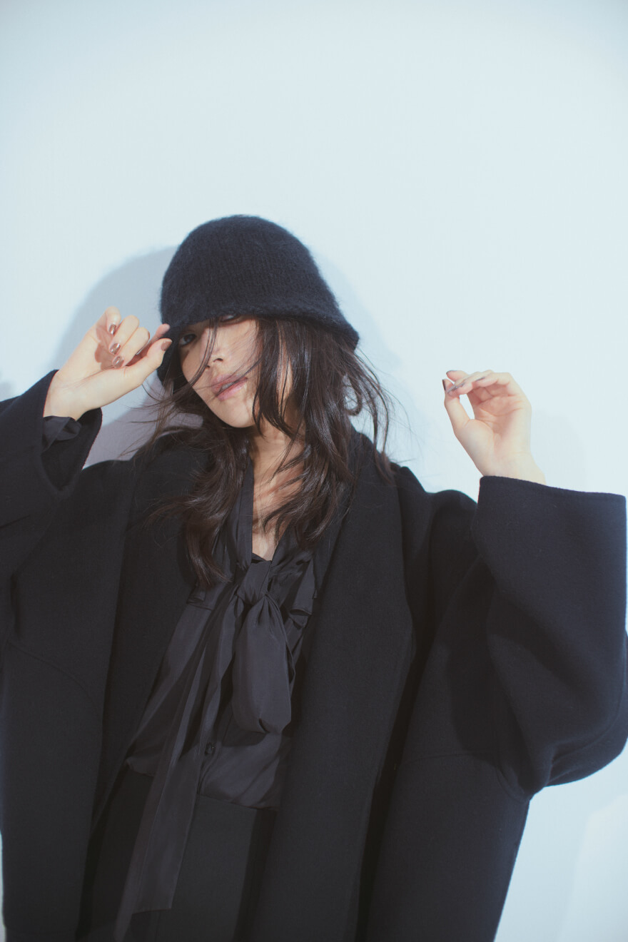 黒コート・黒ブラウス・黒パンツを履いた女性