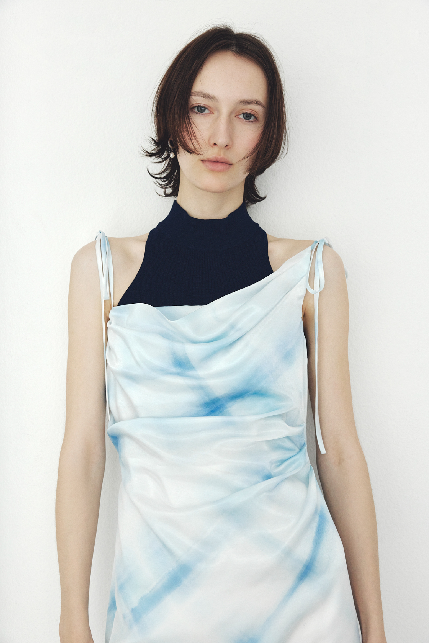 タックドレープキャミワンピース・シルクブレンドカップインホルターニット・フープパールピアスを着用した女性の画像