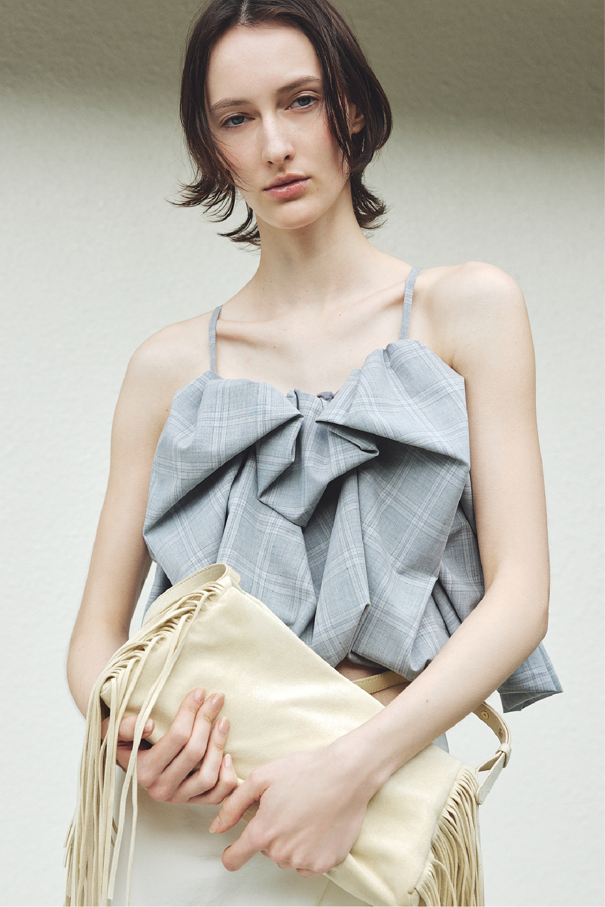 ボリュームパフブラウス・タックドレープビーチスカート・フリンジスラウチバッグを着用した女性の画像