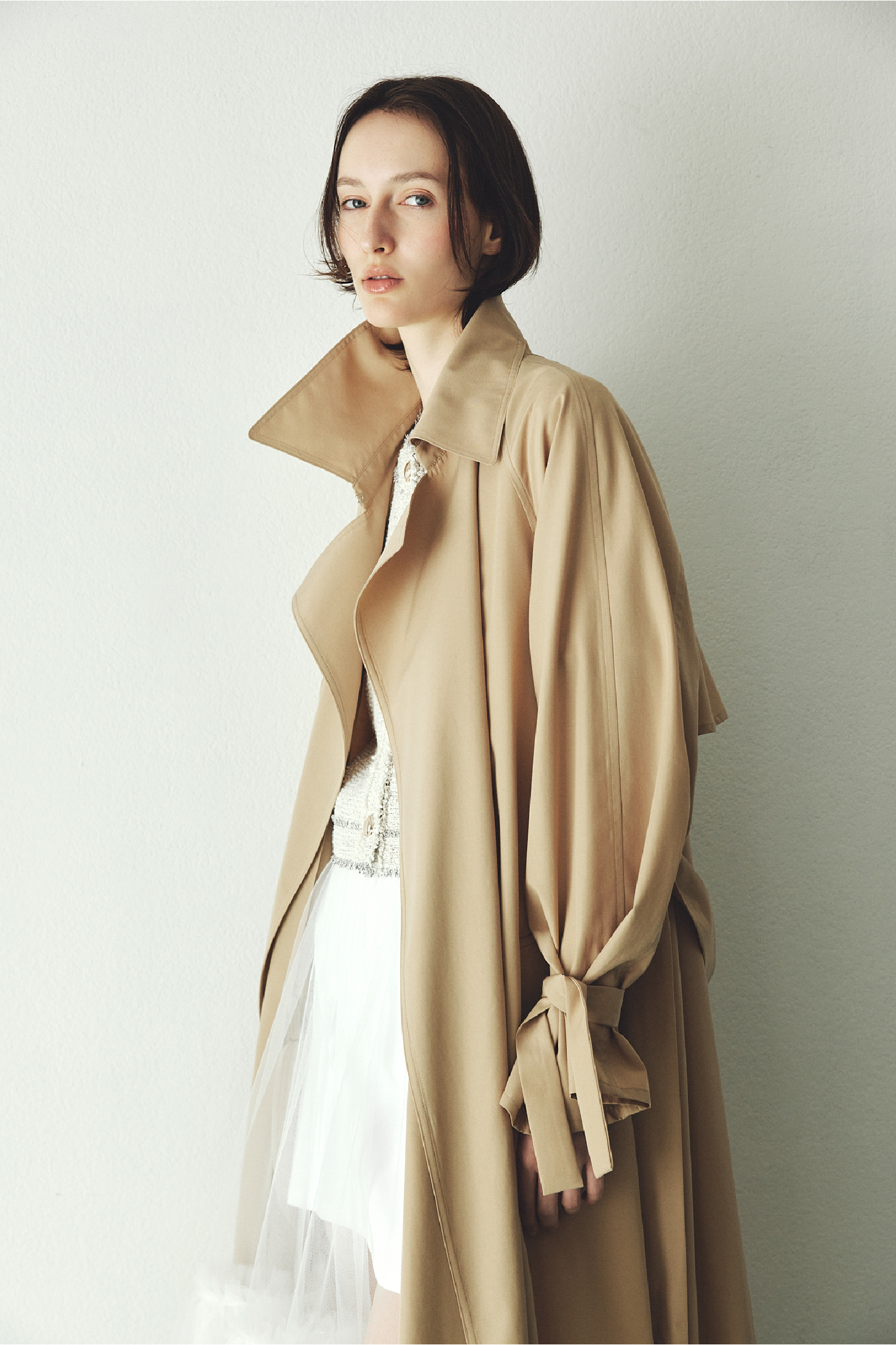 ライトフレアーロングトレンチコート／UVカット・撥水・接触冷・ツイードフリンジ半袖ジャケット・ボリュームギャザーチュールスカートを着用した女性の画像