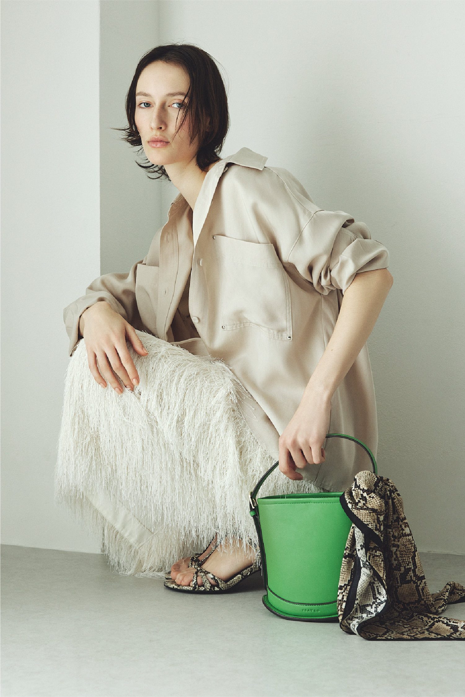 バリエーションシャツ・シャギージャガードストレートスカート・カーブラインミニバスケットバッグ・サテンシルクバリエーションスカーフ・ストラップウィーブサンダル・シルクブレンド前後2way半袖リブニットを着用した女性の画像