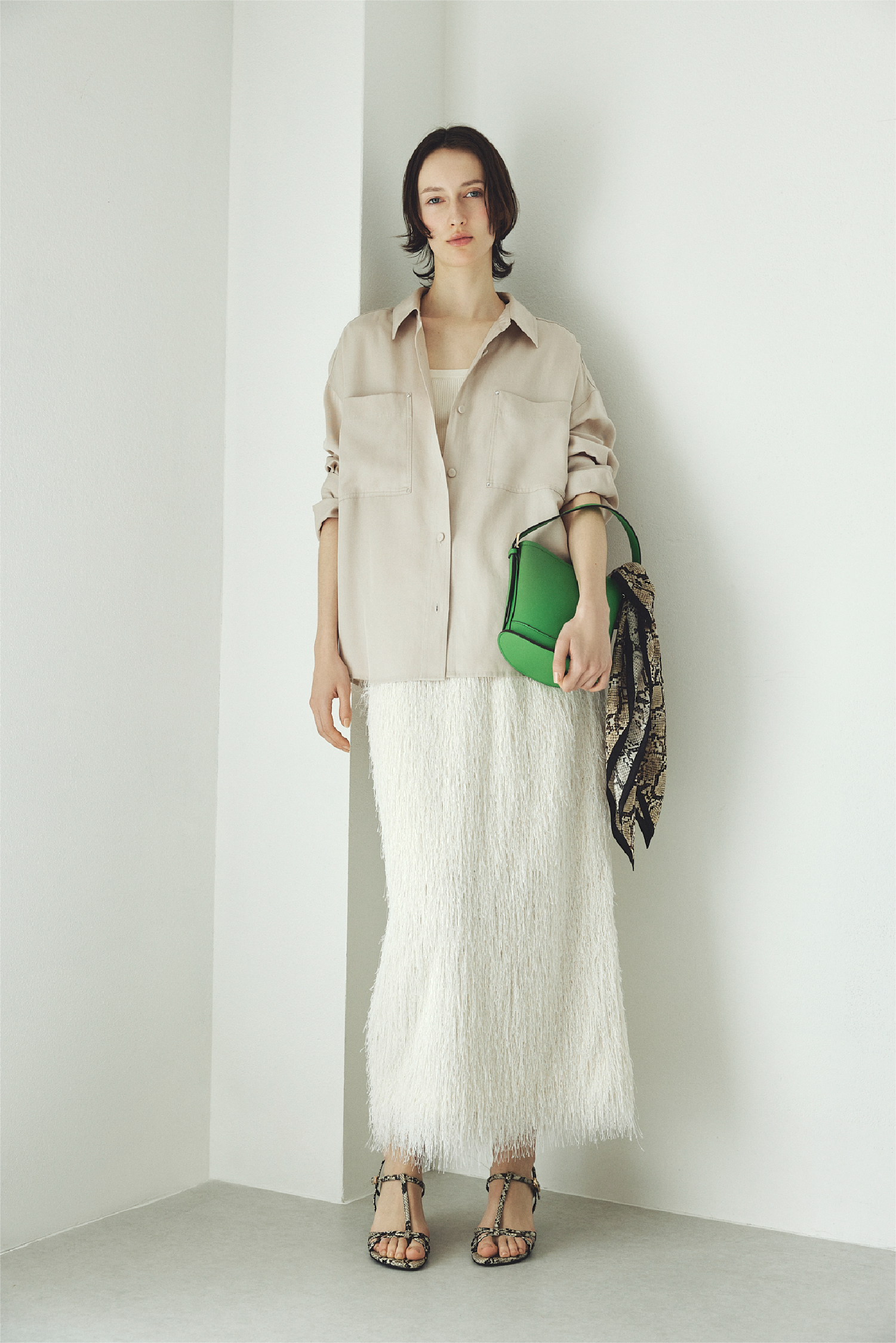 バリエーションシャツ・シャギージャガードストレートスカート・カーブラインミニバスケットバッグ・サテンシルクバリエーションスカーフ・ストラップウィーブサンダル・シルクブレンド前後2way半袖リブニットを着用した女性の画像