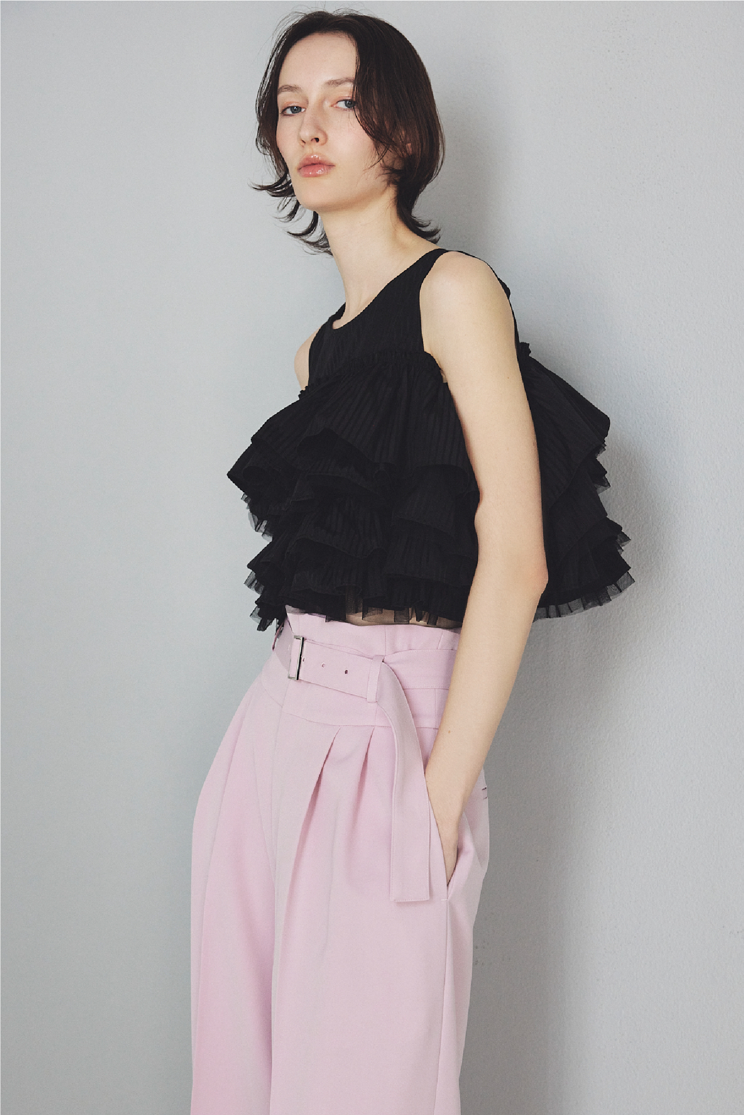 チュールコンビフリルティアードブラウス・ハイウエストベルトパンツ・クリアヒールサンダルを着用した女性の画像